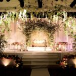 Soft light pink blossom stage decor with delicate floral arrangements and elegant drapery